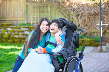 a photo of a young woman hugging a young man who is sitting in a wheelchair